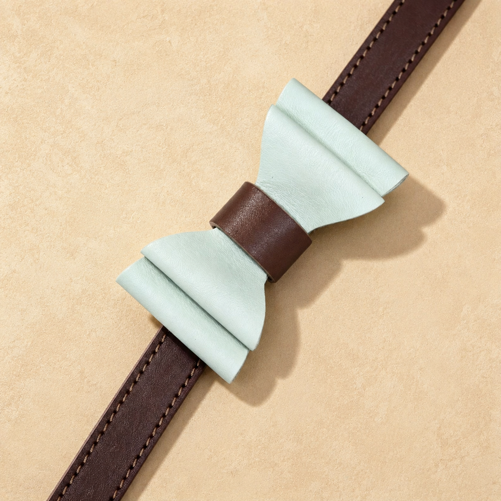 Close-up of a mint green microfibre bow tie attached to a brown full-grain leather dog collar.